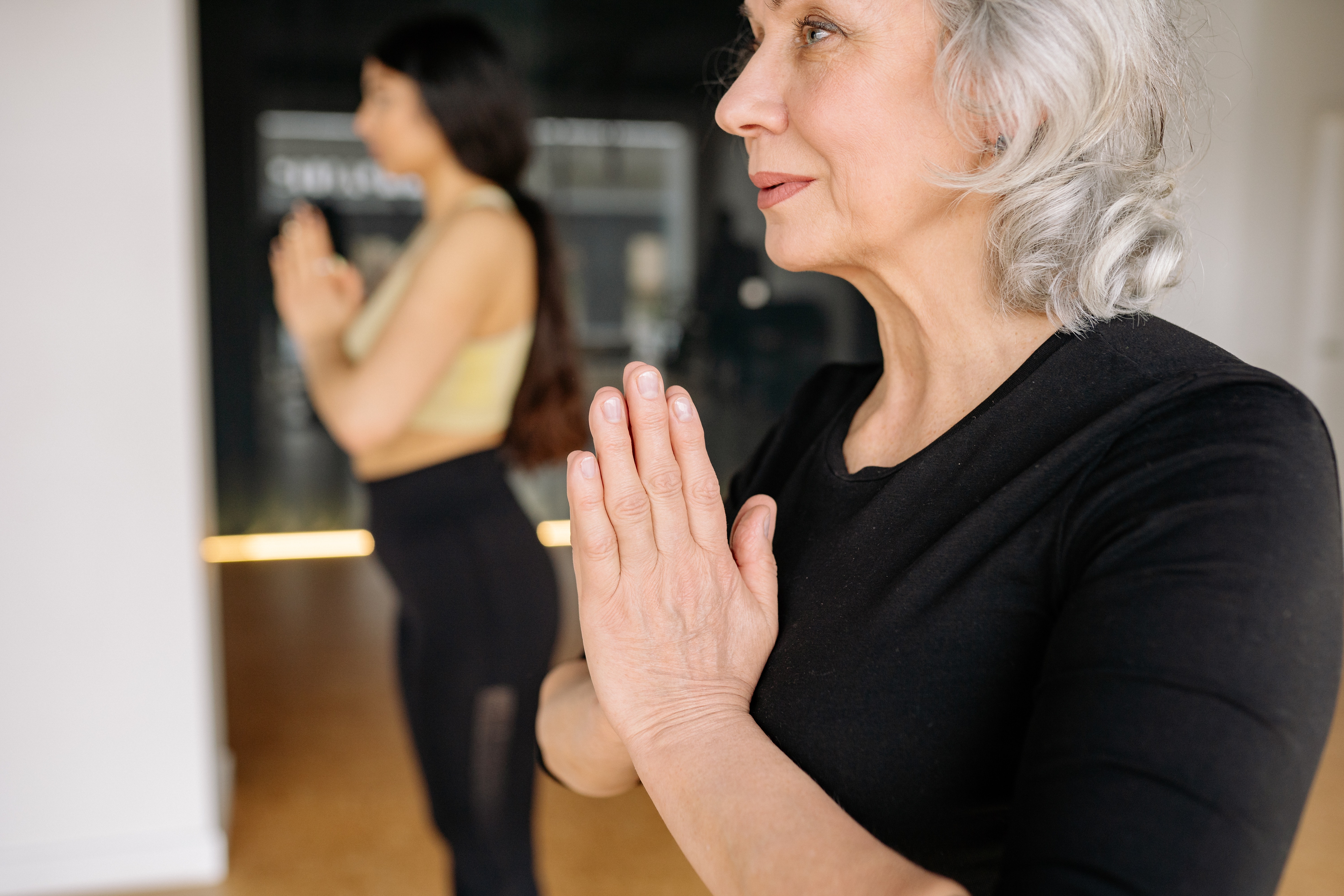femme senior faisant un signe de prière Namasté à la fin d'un cours de yoga